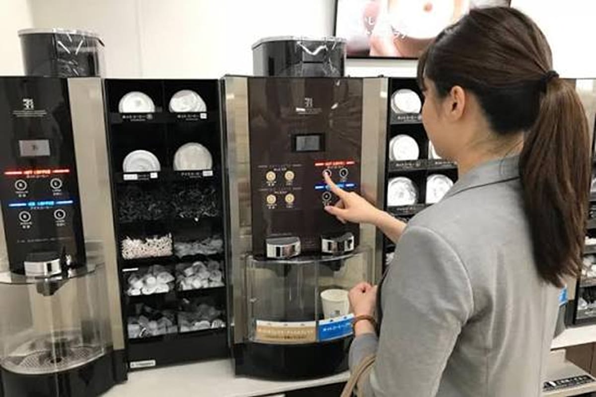 A customer operating a Seven Cafe coffee machine inside a store